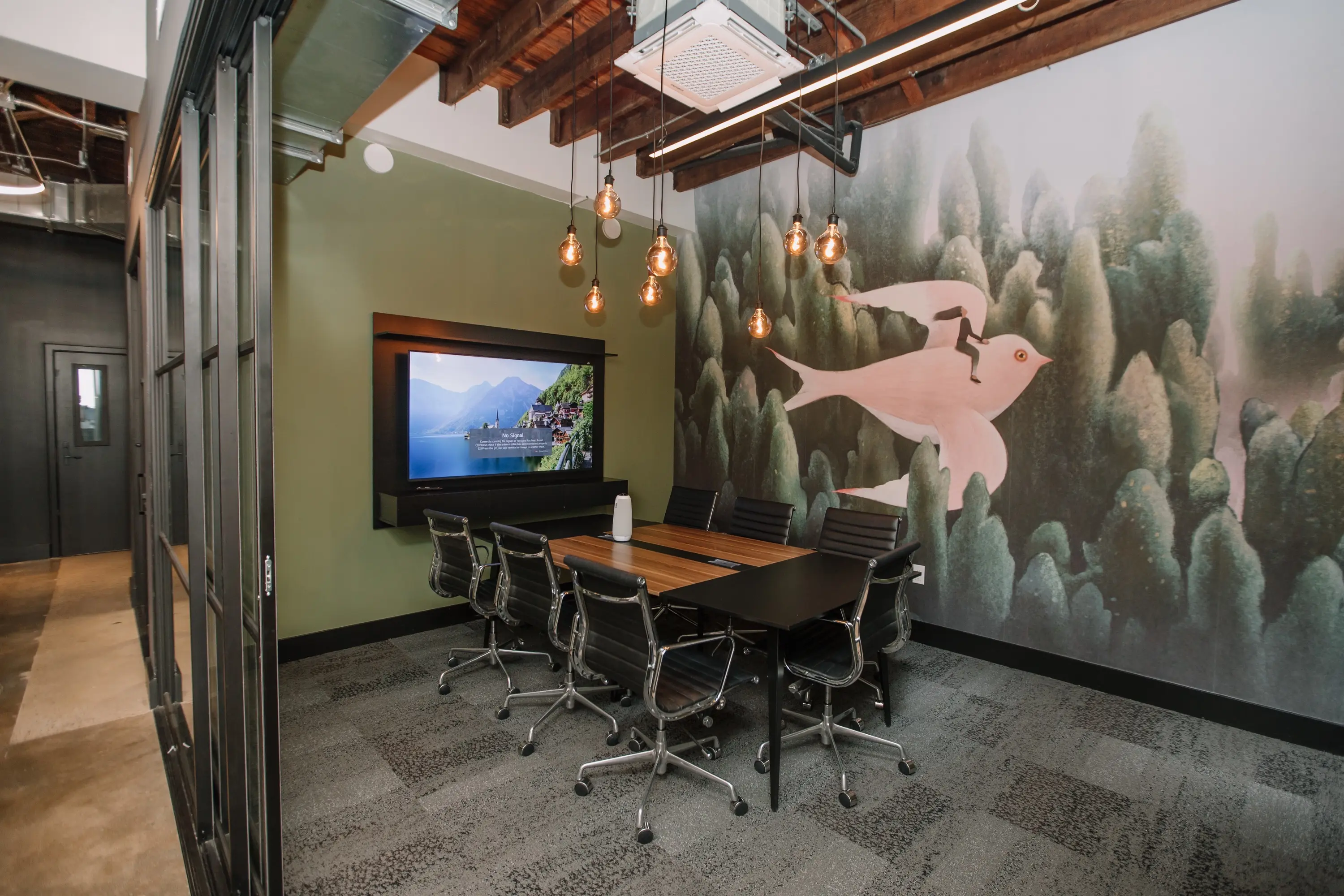 The 8-person conference room with a wall display and pendant lights