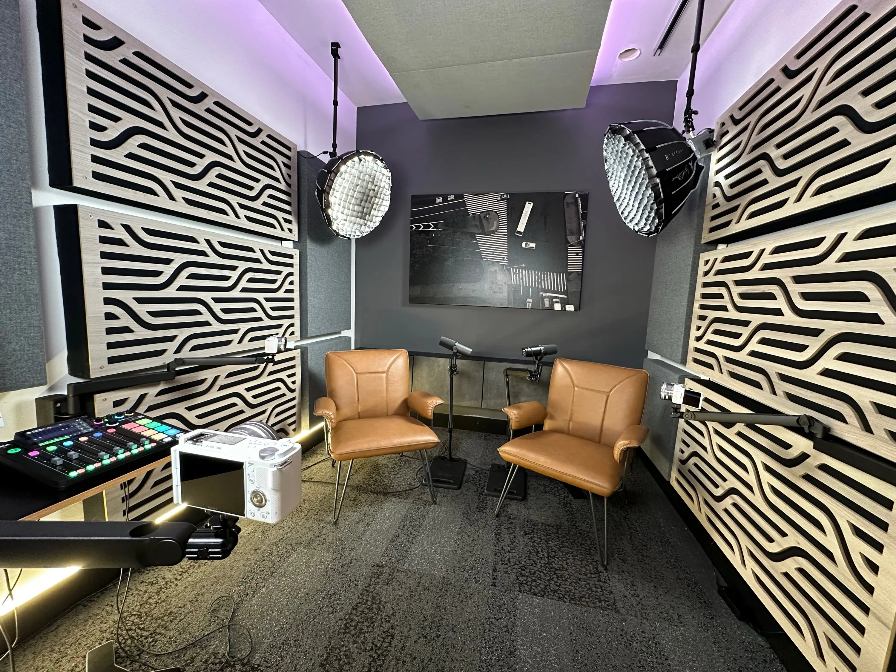 Podcast studio with two leather chairs, microphones, lights and acoustic panels